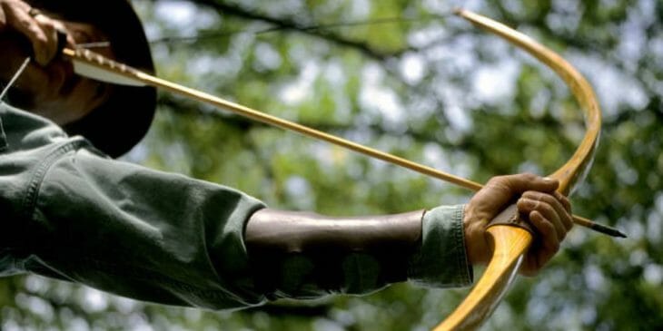 man holding his wooden recurve bow and arrow